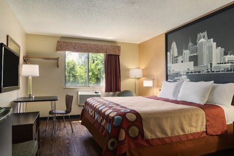 A guest room with a queen bed and a wall mural of the city skyline
