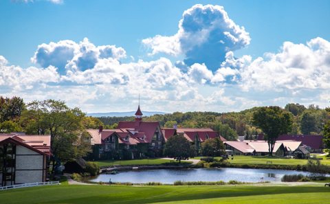 The main lodge and the pond on a sunny summer day with billowing clouds