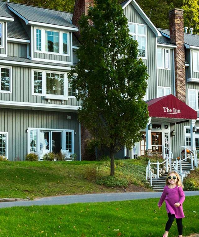 The Inn lodging building's shingled facade with a red name canopy and a lawn in front