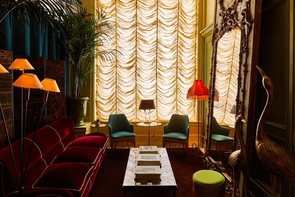 The hotel lounge with a red velvet sofa, floor lamps and ruched curtains