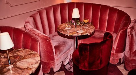 A pink velvet booth with a marble table in the hotel's cocktail bar
