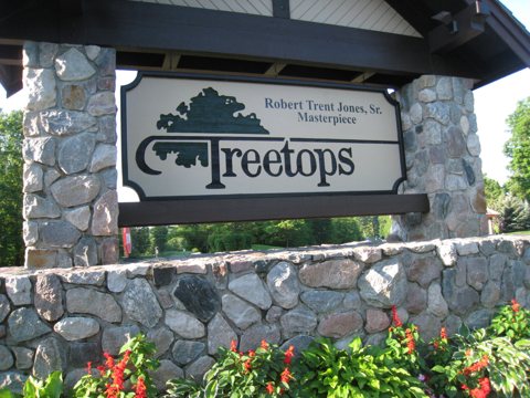 A Treetops kőfalas bejárati táblája virágokkal
