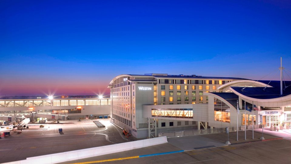 The hotel building lit up next to the McNamara Terminal at dusk