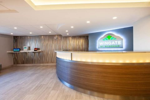 The curved front desk with the lit Wingate sign on the wall
