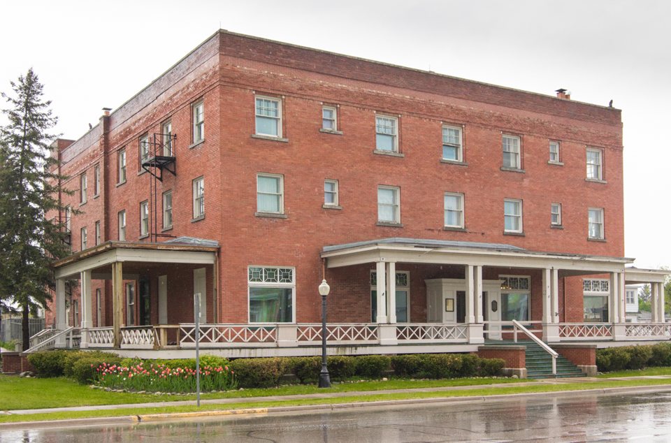 The Wolverine Hotel's three-storey red-brick building with a wraparound porch on Water Street, 2015