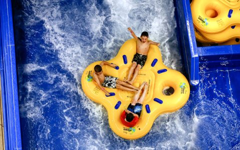 A four-person inflatable tube in the waterpark's rushing channel, seen from above