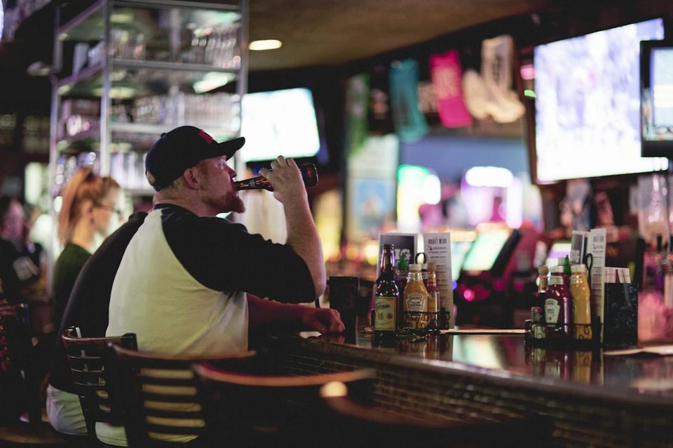 Guests at the bar with drink shelves and TVs behind them