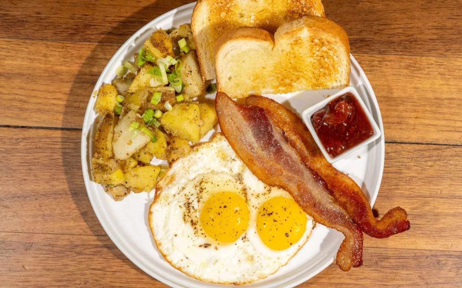 Breakfast plate with sunny-side-up eggs, bacon and potatoes