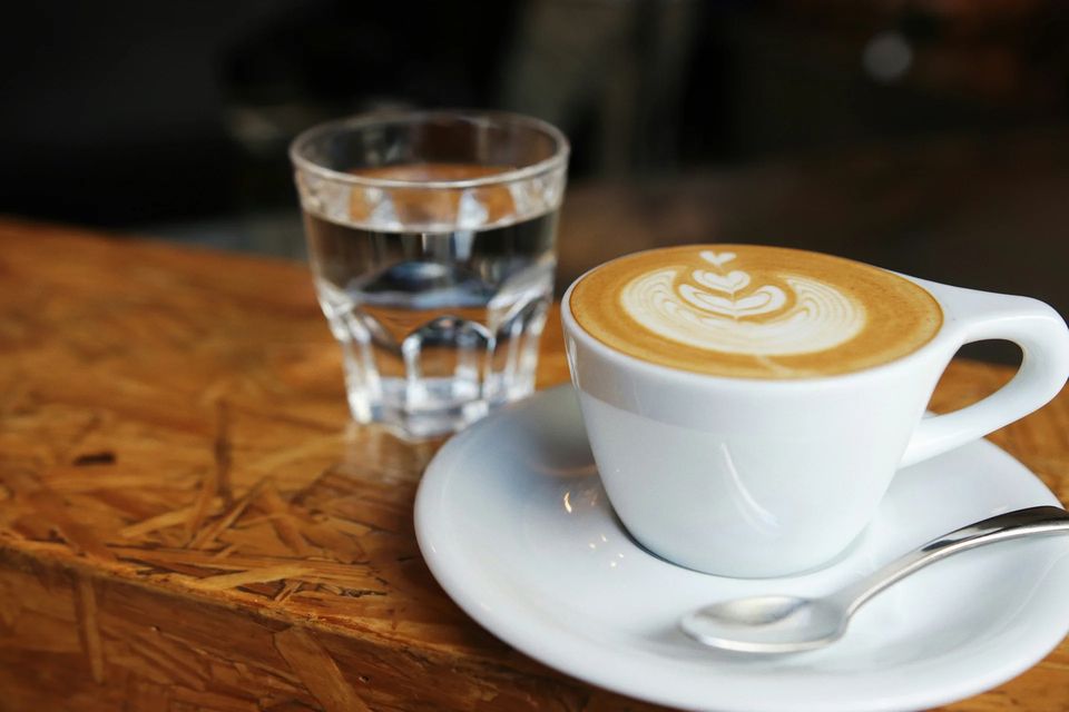 Latte with latte art and a glass of water on a wooden table