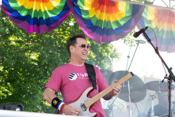 Gitáros lép fel a szivárványos drapériákkal díszített színpadon