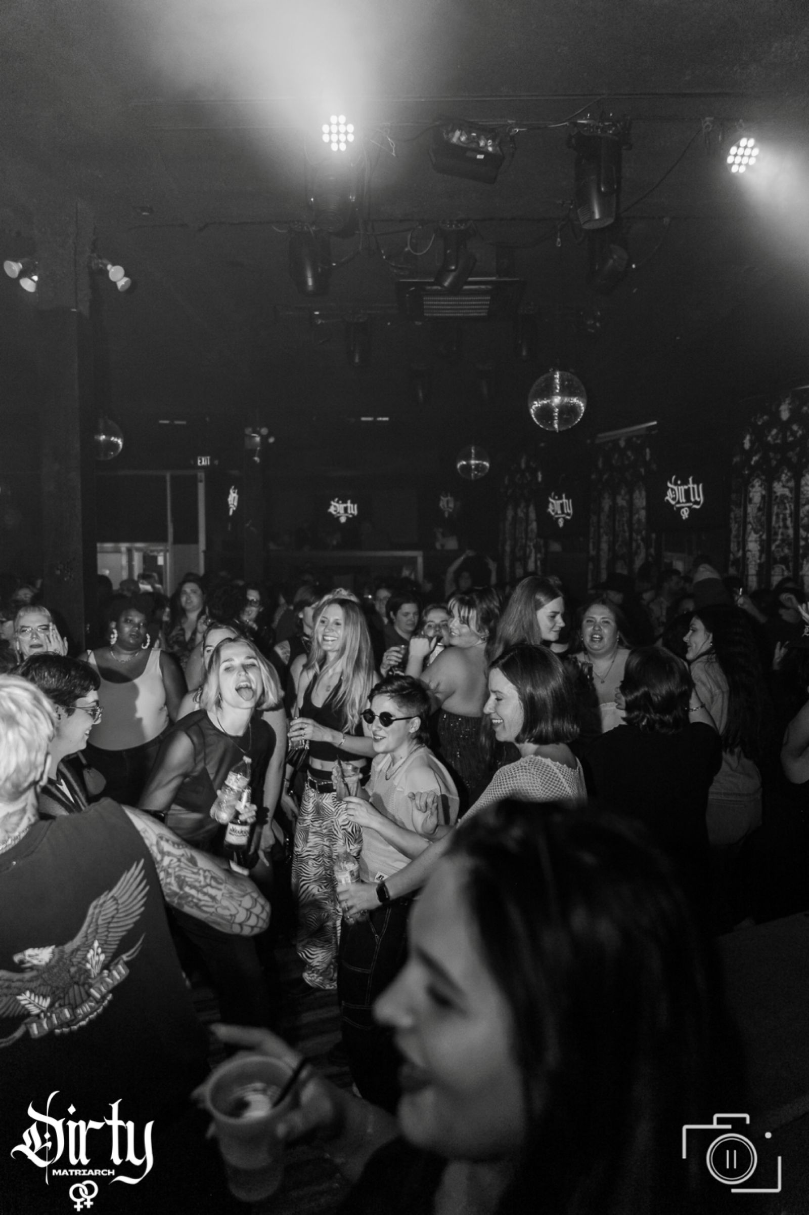 Black-and-white photo of guests dancing at a packed Dirty Matriarch party