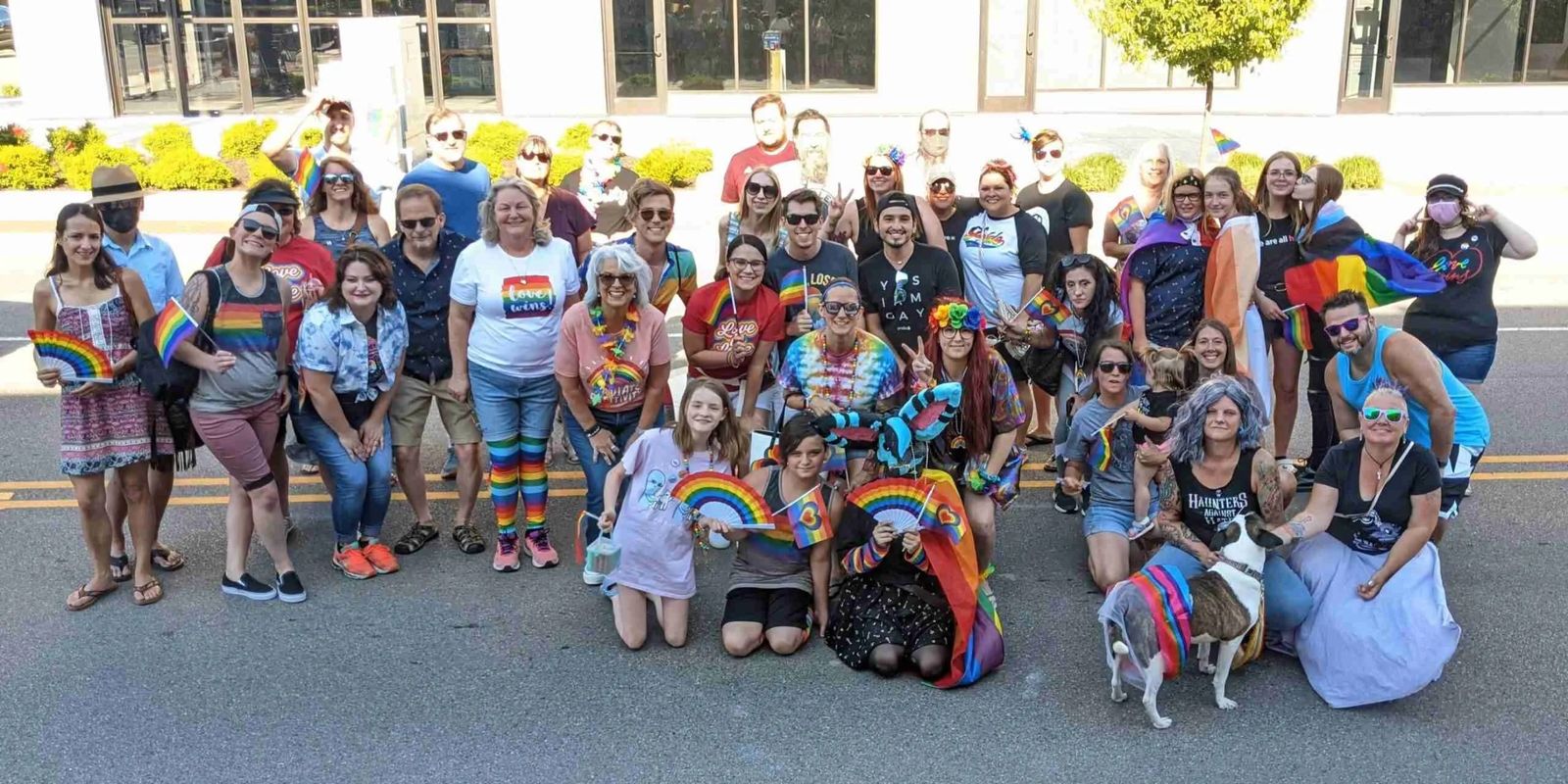 Community group photo with rainbow flags on a sunny street