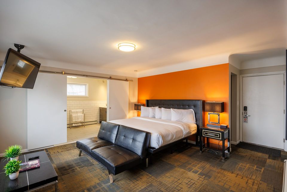 Spacious guest room with a bed, black sofa and TV