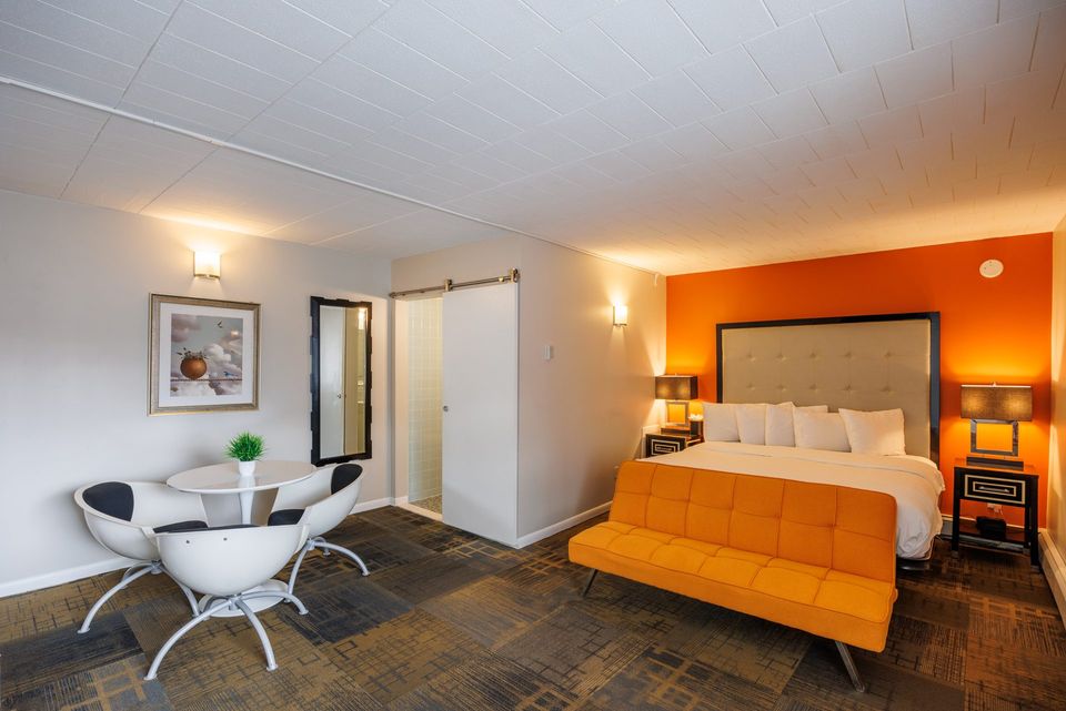 Guest room with an orange sofa and white lounge chairs