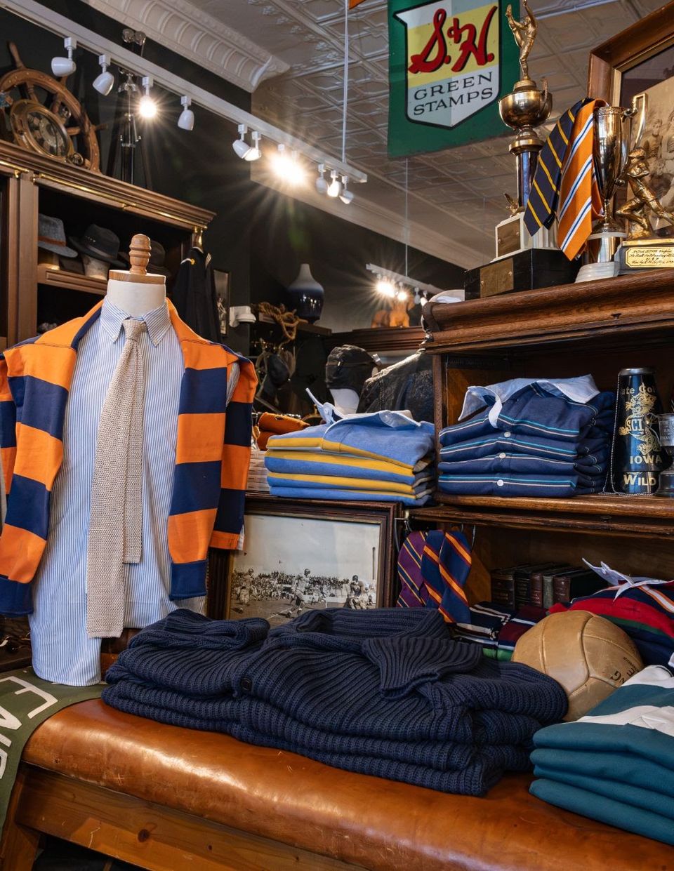 Mannequin in a striped rugby shirt beside shelves of shirts and folded knit sweaters