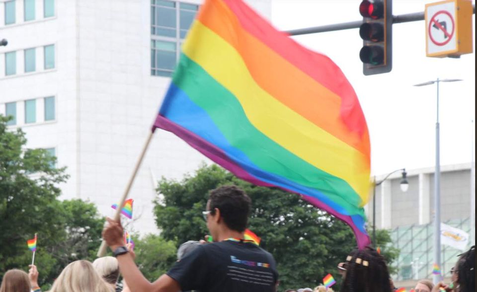 Szivárványzászlót lengetnek a tömeg fölött egy Pride-felvonuláson