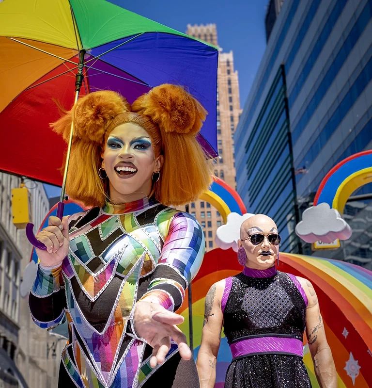 Szivárványos jelmezes drag-előadó esernyővel a Motor City Pride-on