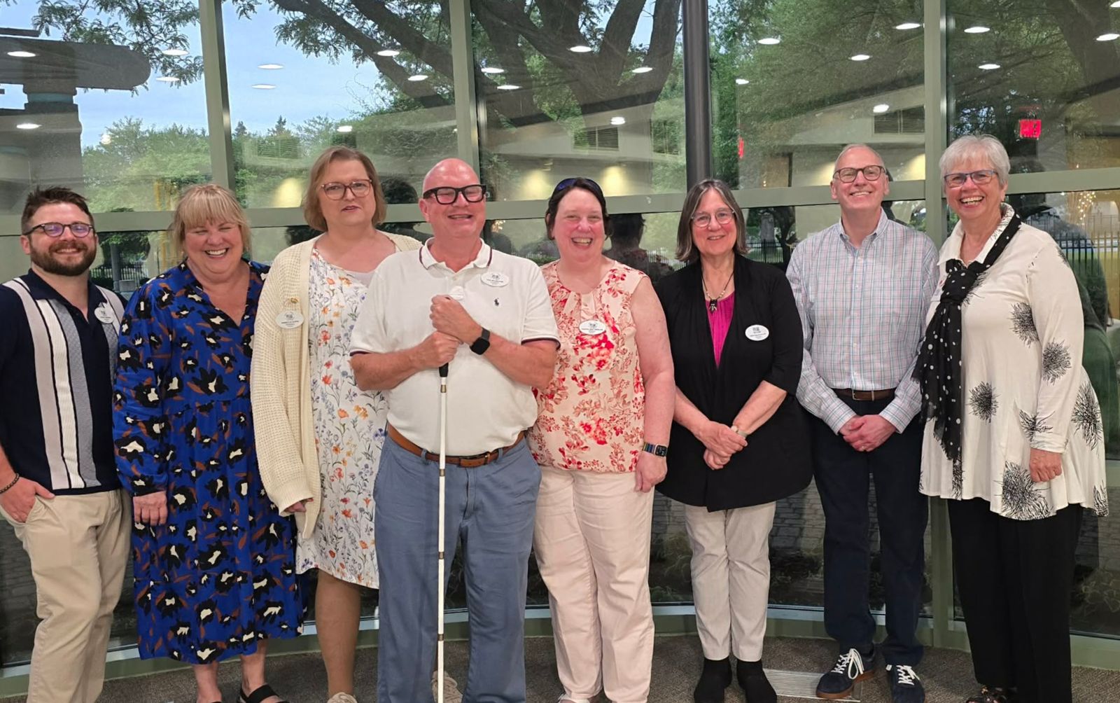 Smiling chapter members pose together in a glass-walled lobby