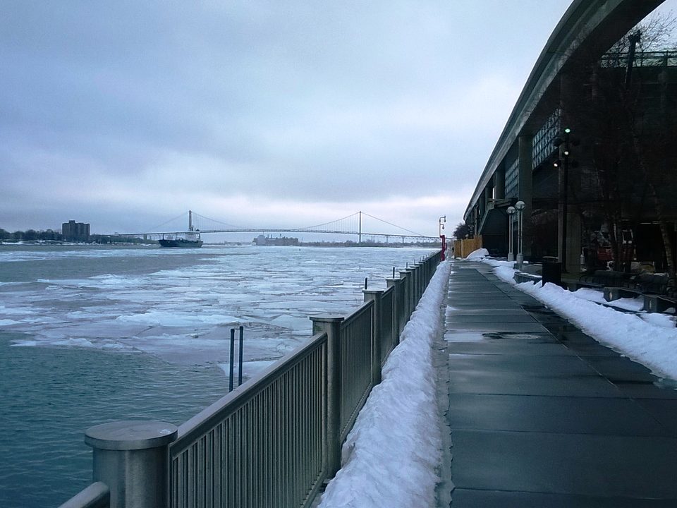 The frozen riverfront beside the guideway, with the Ambassador Bridge beyond (2014)