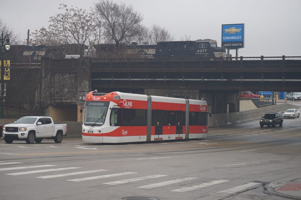 Villamos a vasúti felüljáró alatt, fent egy Norfolk Southern tehervonat (2021)