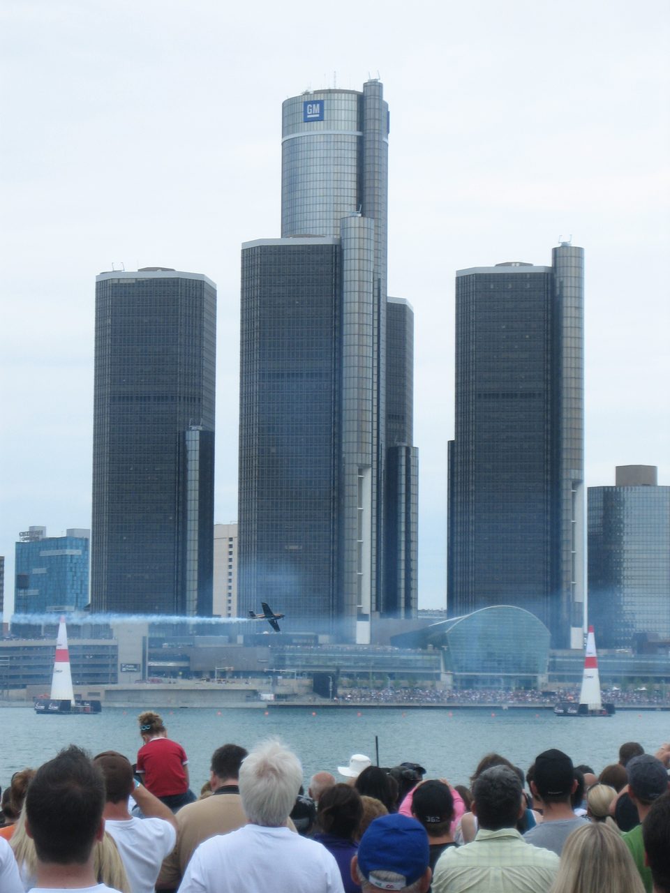 Nézők a 2009-es Red Bull Air Race-en Windsorban: egy versenygép a víz fölött repül a kapuk között, mögötte a Renaissance Center