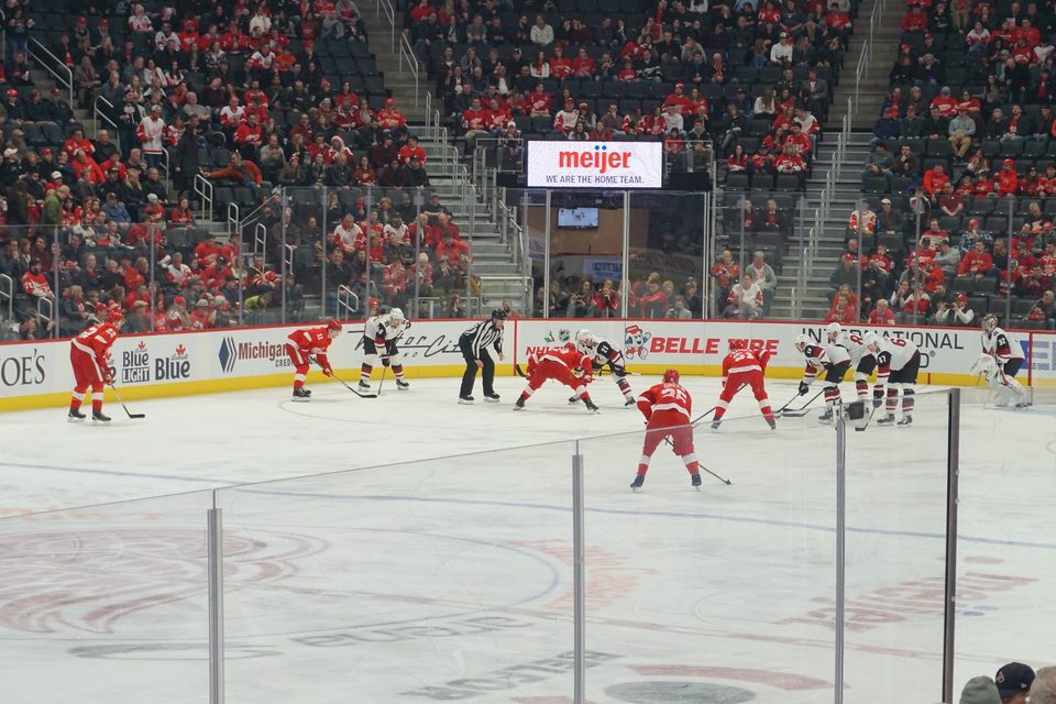 Bedobás a Red Wings és az Arizona Coyotes meccsén a Little Caesars Arenában, piros mezes szurkolókkal a plexi mögött