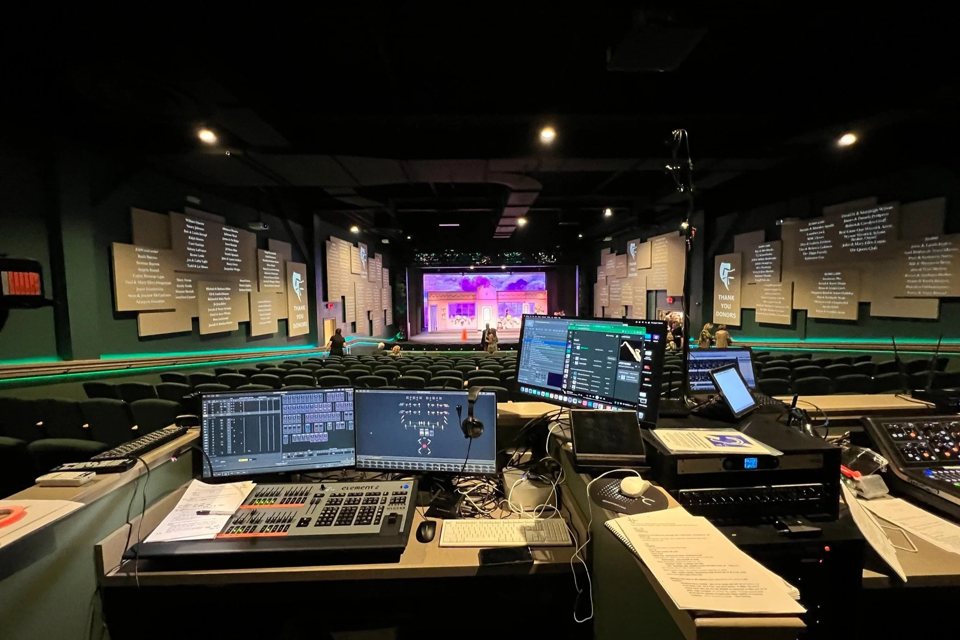 The Boardwalk Theatre auditorium seen from the sound and lighting desk, with green seats, donor panels on the walls and a lit set on stage