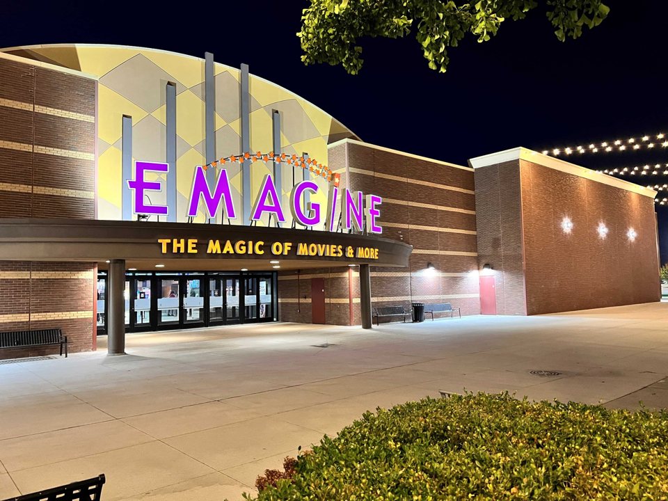The curved facade of Emagine Novi at night, with purple EMAGINE letters and a lit entrance canopy