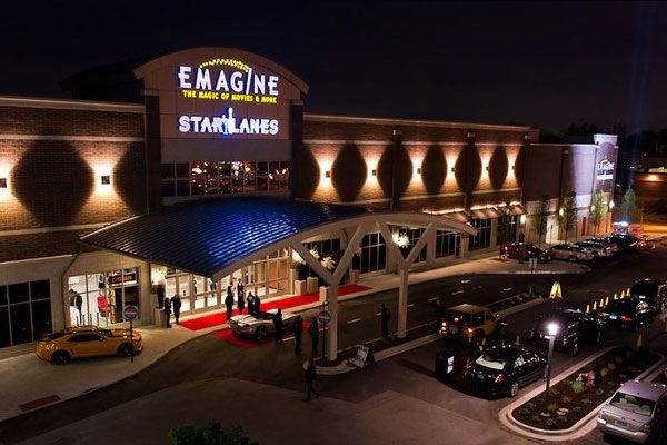 The Emagine and Star Lanes building at night from above, with a red carpet, a lit canopy and cars at the entrance
