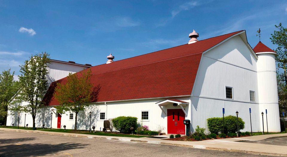 The Farmington Players' white barn theatre with its red roof, red doors and silo tower among spring trees