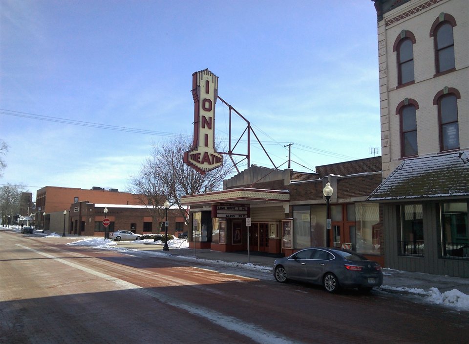 The Ionia Theatre's tall vertical sign and marquee on a snowy downtown street in winter