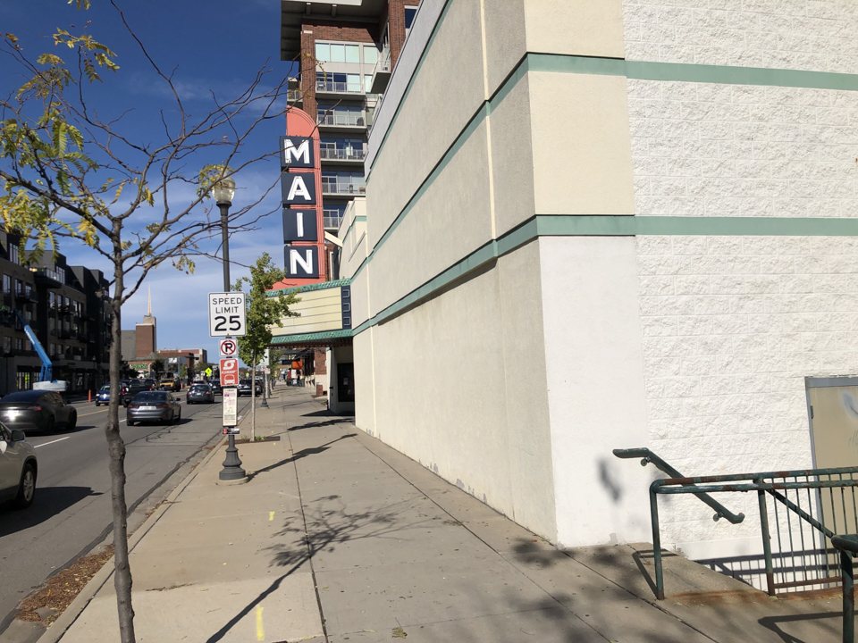 The shuttered Main Art Theatre's pale side wall and vertical sign on Main Street in October 2021