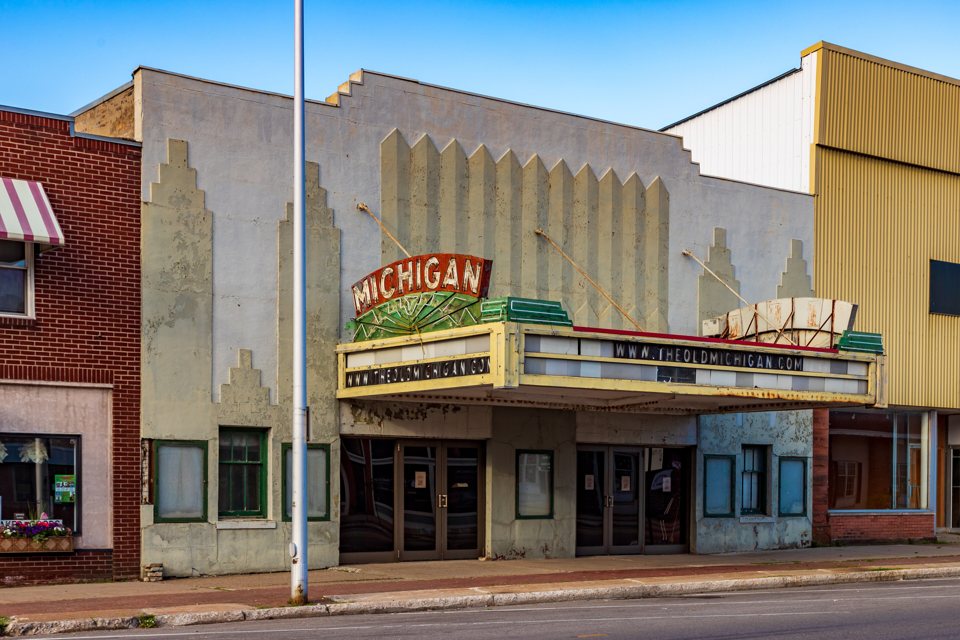 The Art Deco facade of the Michigan Theatre on Ludington Street in Escanaba, with its red-and-green MICHIGAN sign and marquee