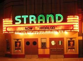 The green STRAND neon sign and bulb-lined marquee lit up at night