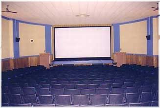 The auditorium with rows of blue seats facing the white screen