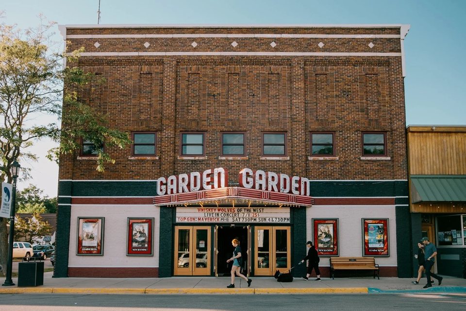 The Garden Theater's brick facade with its double GARDEN sign and marquee, people walking past on a sunny afternoon