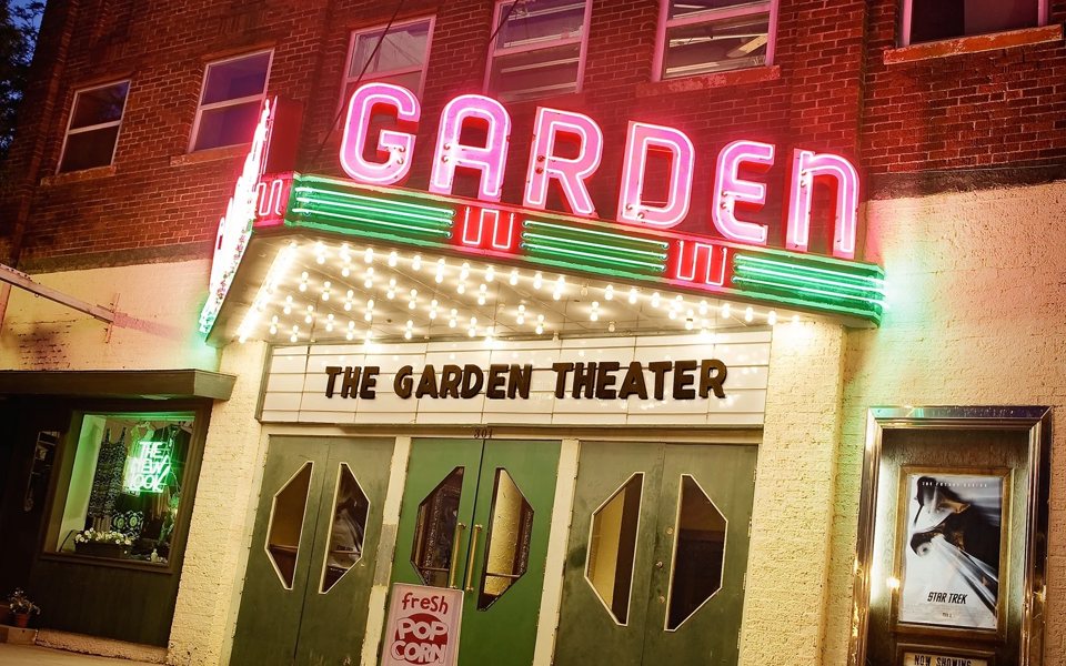 The pink and green neon GARDEN sign and bulb-lined marquee above the green entrance doors