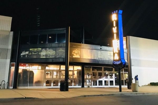 The cinema's glass-front entrance at night, with the vertical blue-lit Riviera Cinema sign