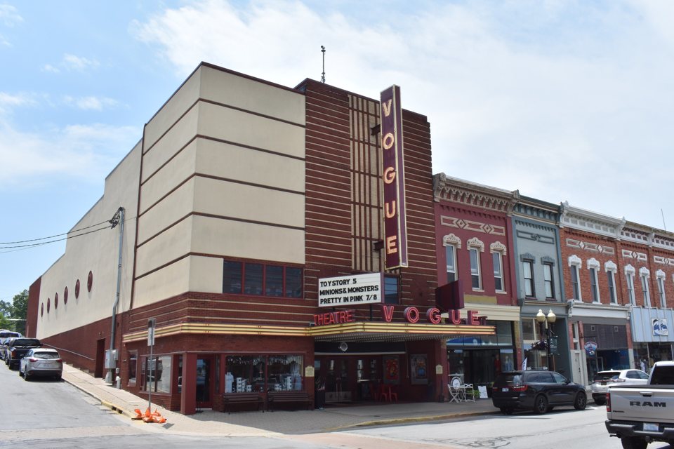 The Vogue Theatre's art deco facade in Manistee with its vertical VOGUE sign and marquee listing the films