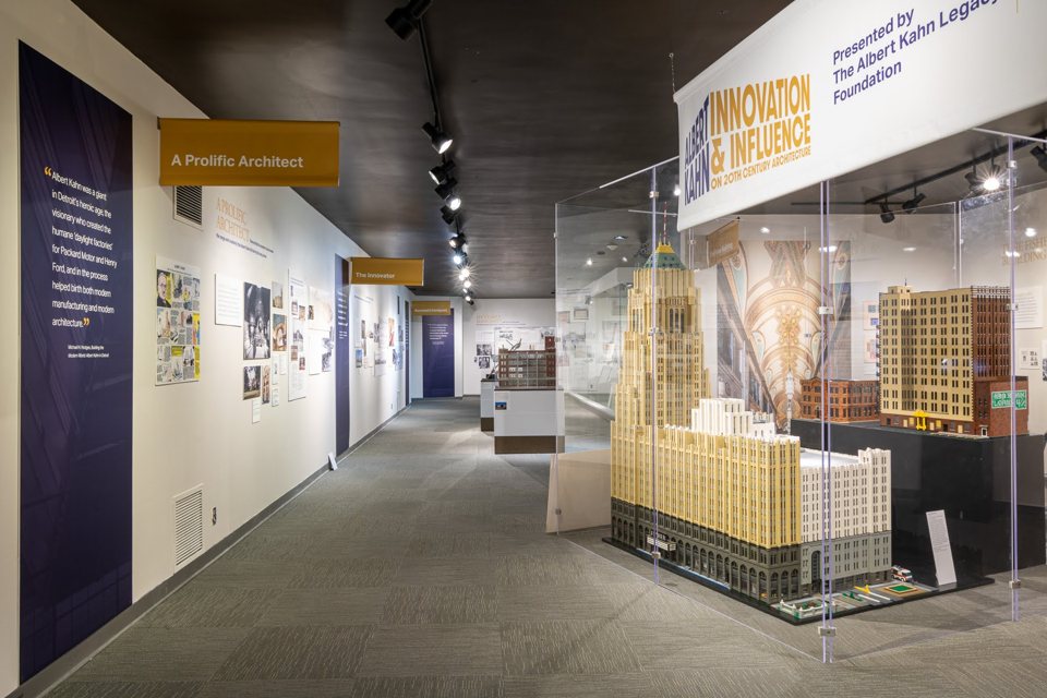 A museum hallway with model buildings and panels about Albert Kahn's architectural work