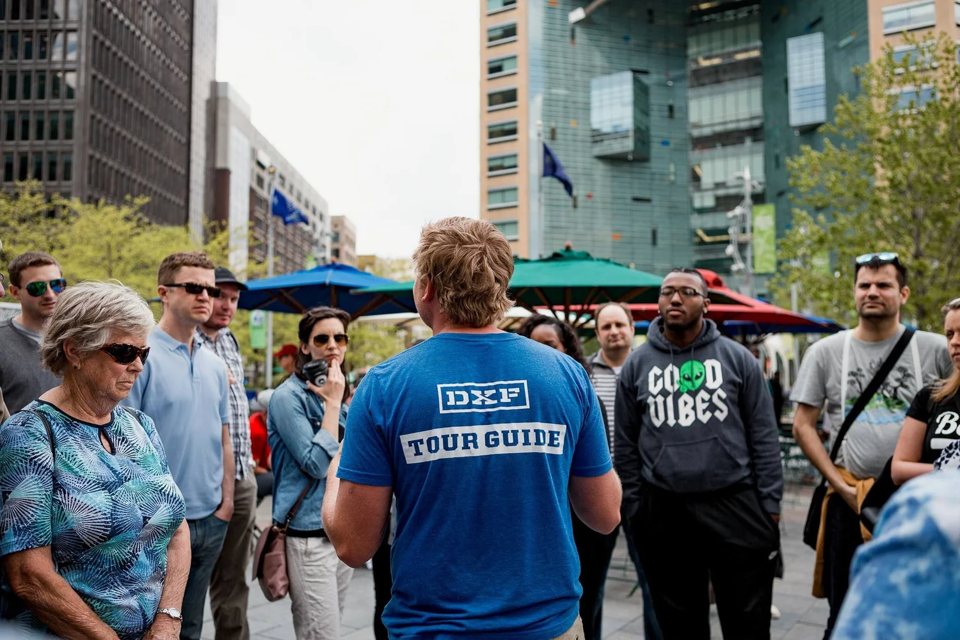The tour guide talks to the group in downtown Detroit