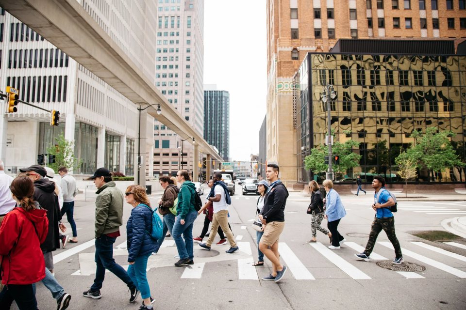 The tour group crosses the street downtown, with the People Mover track overhead