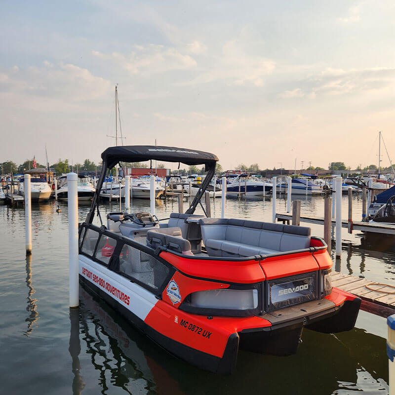 Detroit Sea-Doo Adventures' red boat docked at the marina at sunset