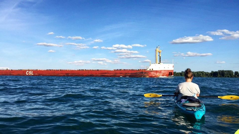 A kayaker watches a large freighter pass by on the Detroit River