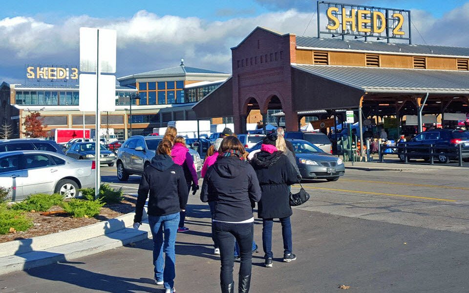 Csoport sétál az Eastern Market Shed 2 épülete felé a parkolón át napsütéses időben