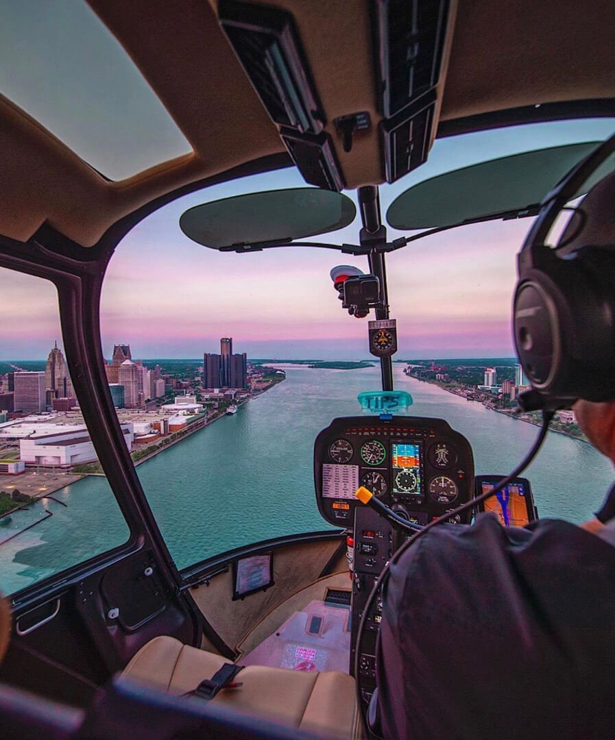 View from inside the helicopter cockpit at sunset over the Detroit River and downtown skyline
