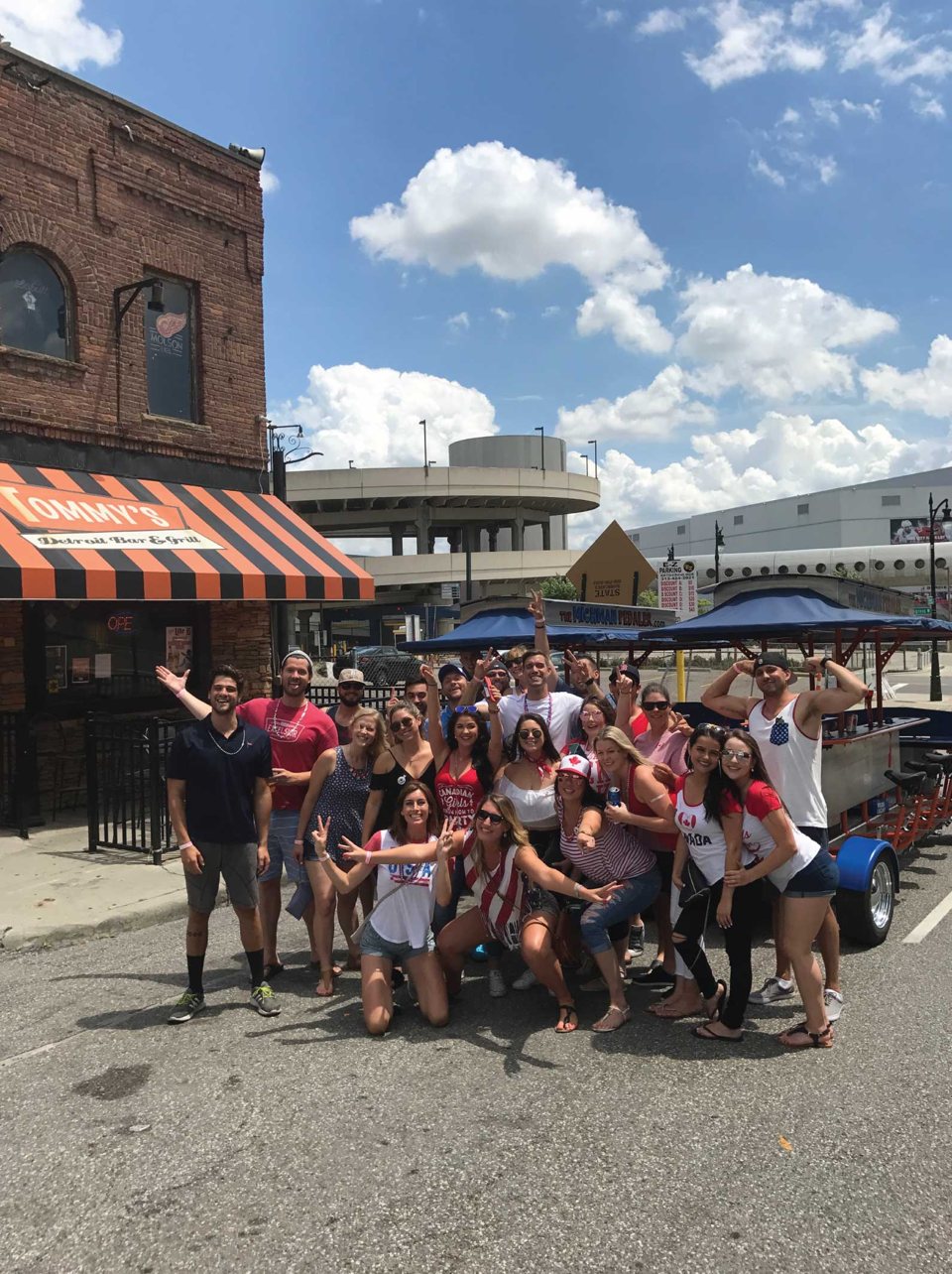 A large group poses outside Tommy's Bar & Grill next to the party bike