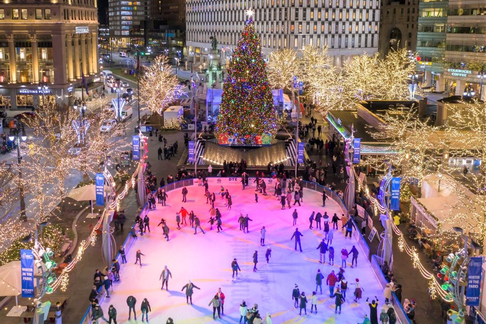 Aerial night view of the Campus Martius ice rink with a lit Christmas tree and skaters