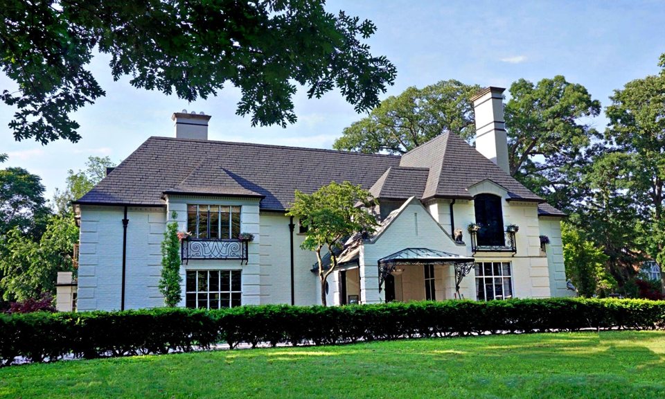 A grand historic home stands in Palmer Woods' sunlit garden