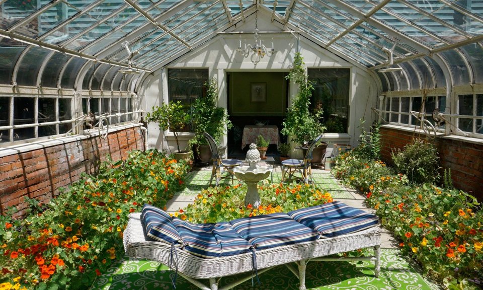 A glass conservatory filled with blooming plants inside a Palmer Woods home
